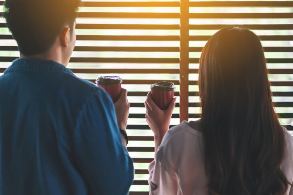 A loving couple staring through the blinds.