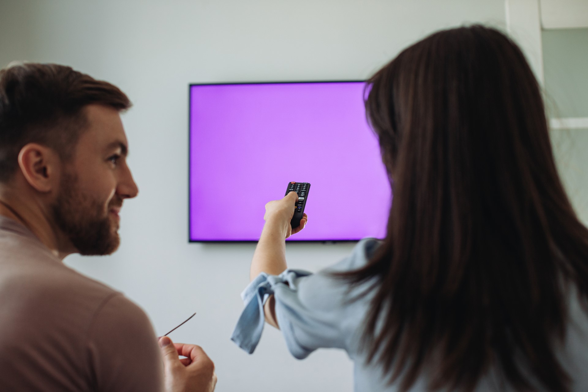 Happy couple watching a TV mounted by Wehr There, LLC.